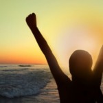 woman-with-arms-raised-at-sunset-on-the-beach